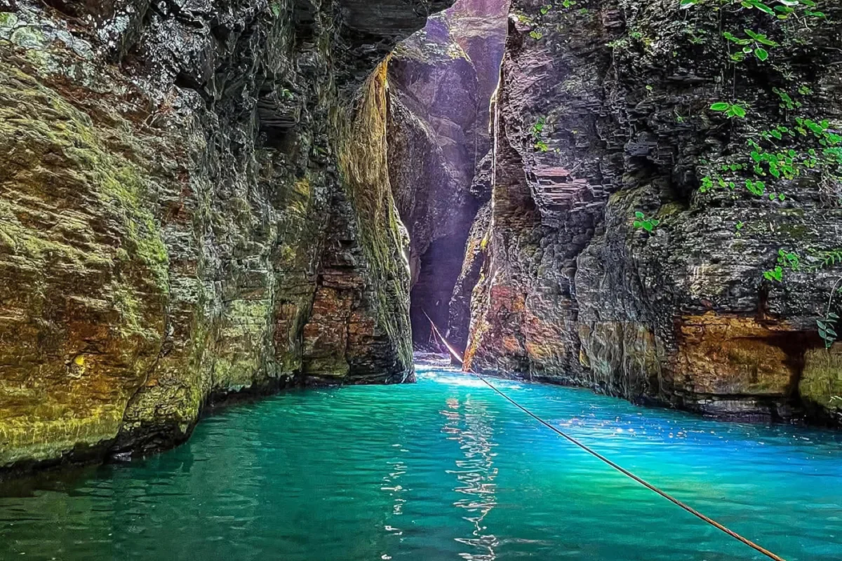 Narrow volcanic rock canyon with glowing turquoise water and guide rope leading toward La Leona Waterfall, Guanacaste Costa Rica