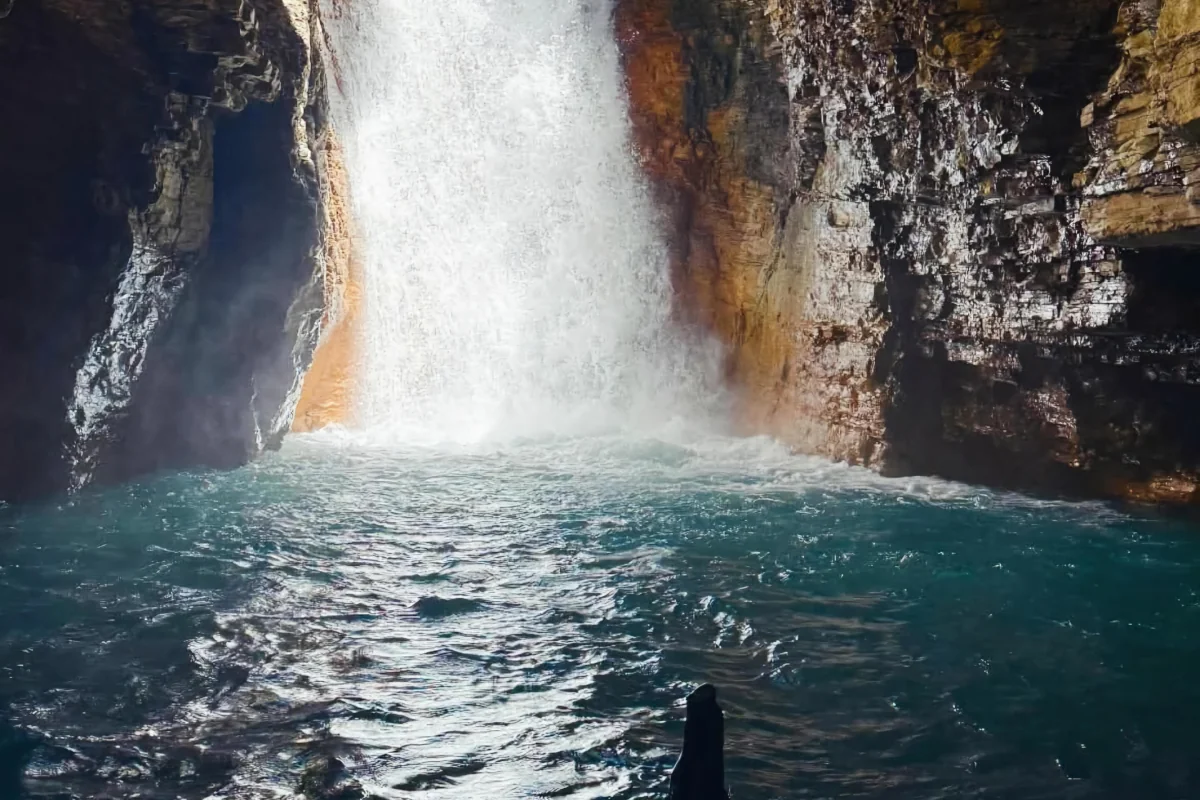 View from inside the volcanic rock canyon looking up at La Leona Waterfall with turquoise blue water, near Rincón de la Vieja, Guanacaste Costa Rica