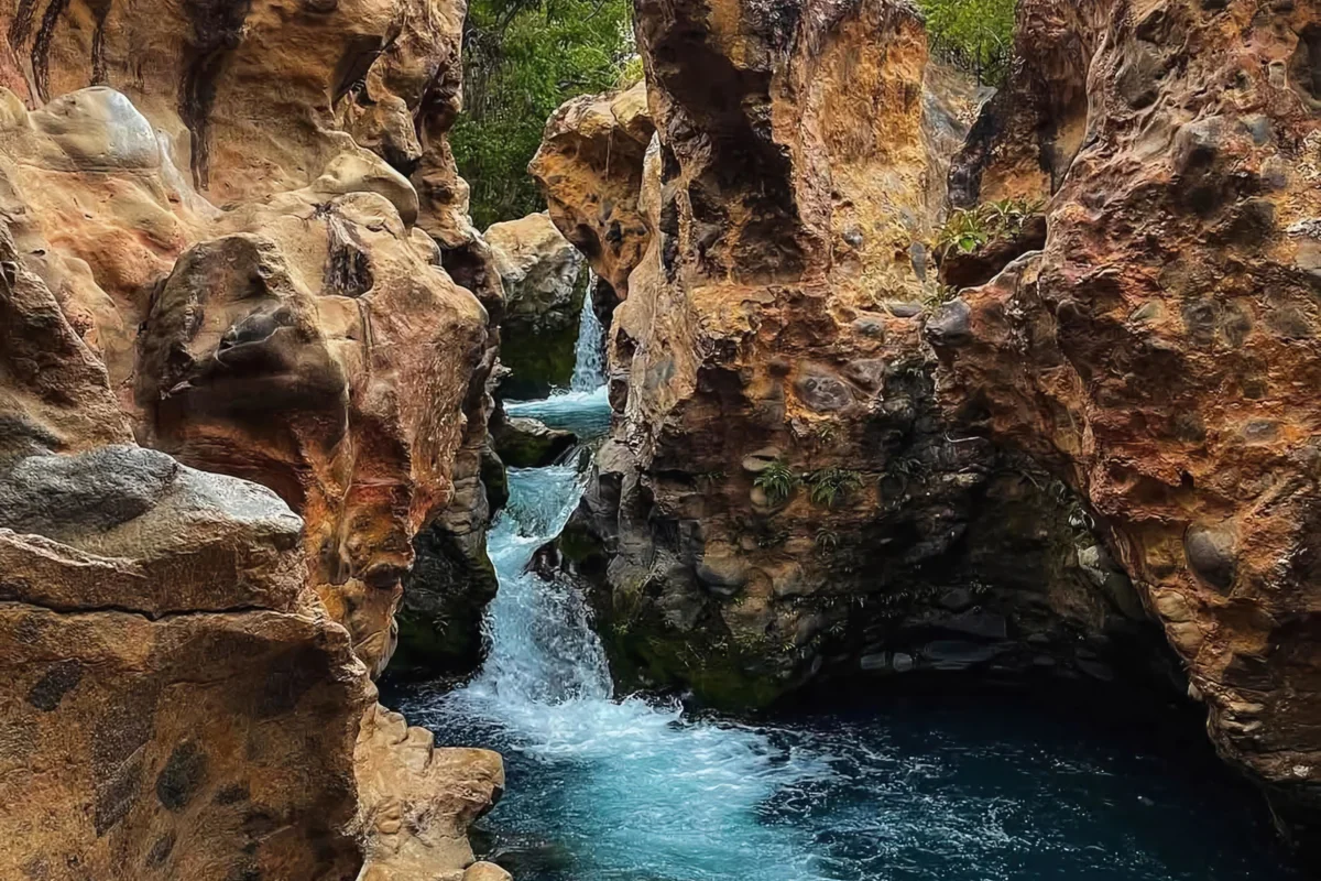 Overhead view of volcanic rock canyon with bright turquoise pools and cascading water at La Leona near Rincón de la Vieja, Guanacaste Costa Rica