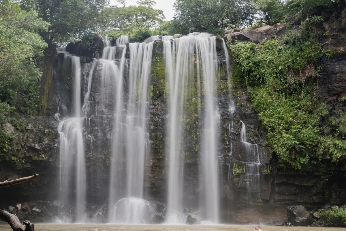 Long exposure shot of Llanos de Cortez waterfall with silky cascading water over moss-covered rocks in Guanacaste, Costa Rica