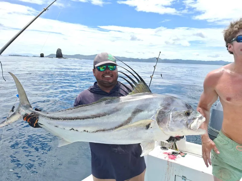 Captain holding a large roosterfish on a Playa Flamingo fishing charter