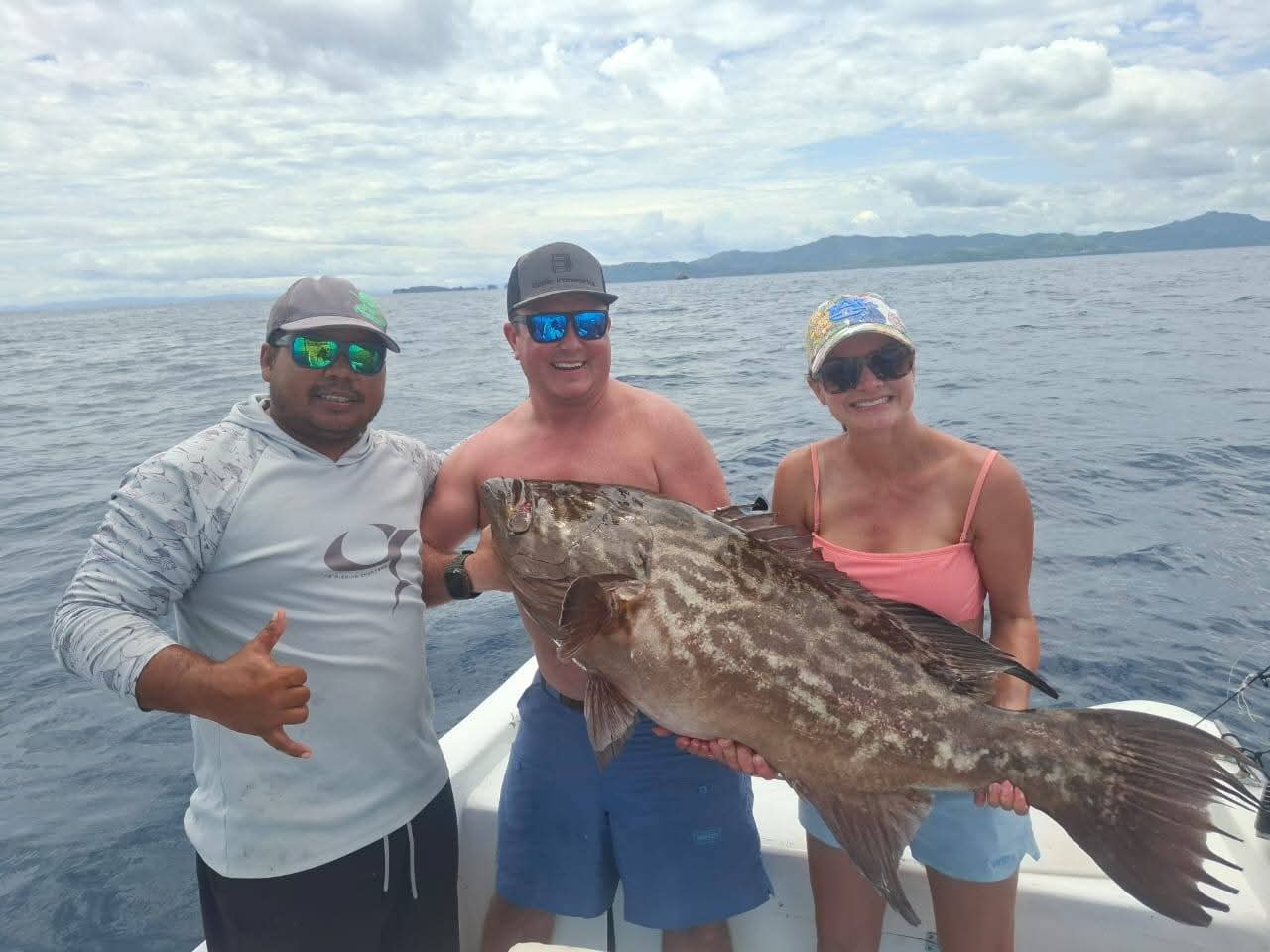 Captain and guests holding a large grouper on a Costa Rica fishing charter