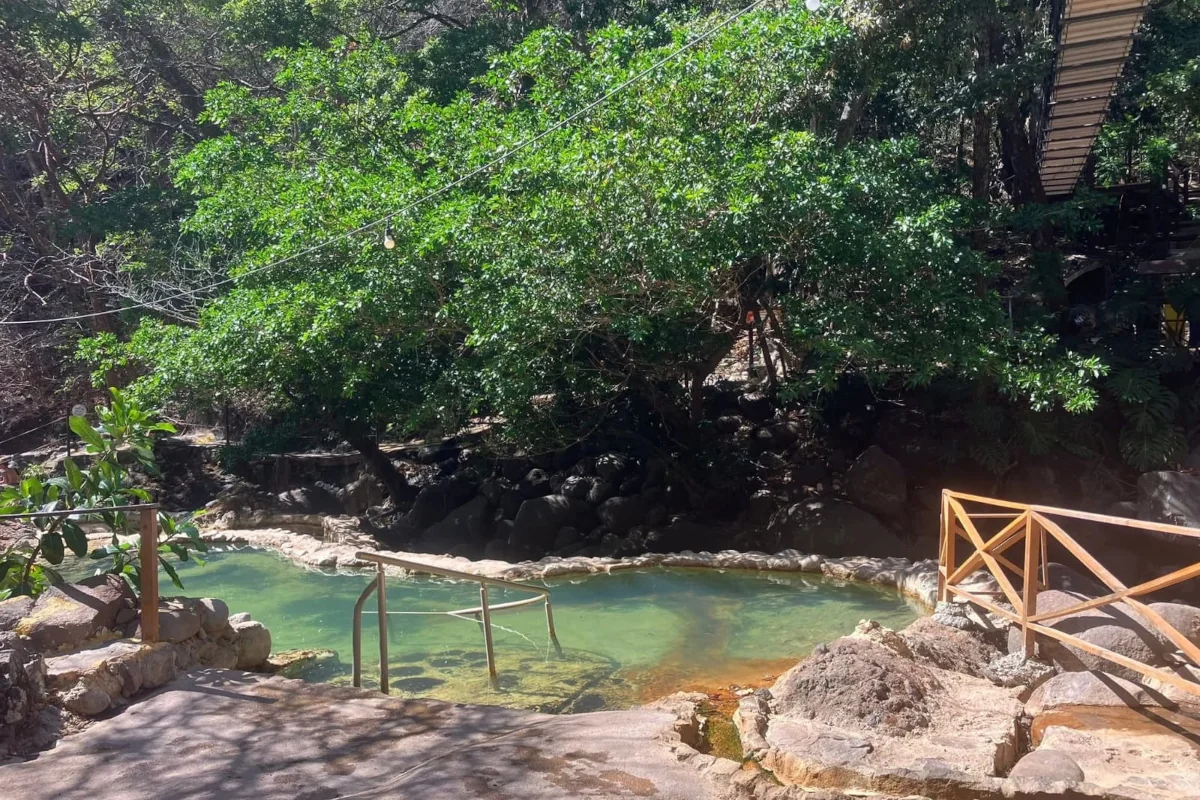 Aerial view of guests soaking in natural volcanic hot spring pools surrounded by jungle at Rio Negro near Rincón de la Vieja, Guanacaste Costa Rica